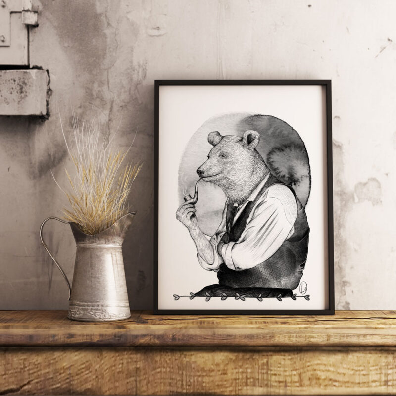 Cornice nera con all'interno l'illustrazione di un orso antropomorfo che fuma una pipa. Il quadro è appoggiato su un piano in legno, accanto un vaso in metallo con dei fili di paglia gialli.